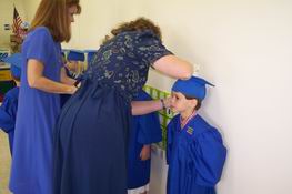 His teachers helping with his cap