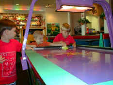 Alex is showing Carter how to play air hockey